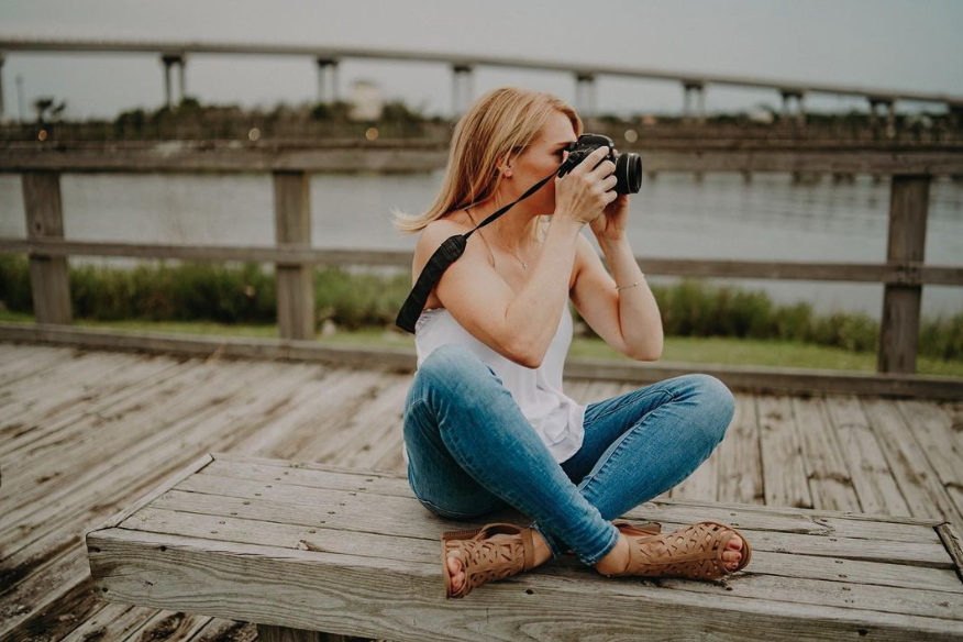 blonde girl in white shirt and jeans looking through the camera viewfinder